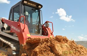 A TL8 front end loader with a scoop of dirt against a cloud and sky backgrounf