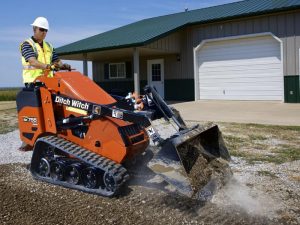 a man operating an SK750 in front of a house construction