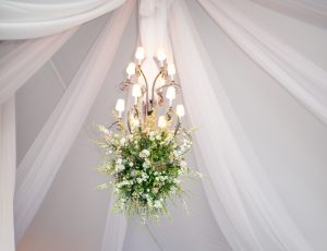 iron chandelier underneath a lit tent during a wedding