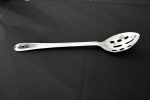silver slotted spoon on a black background